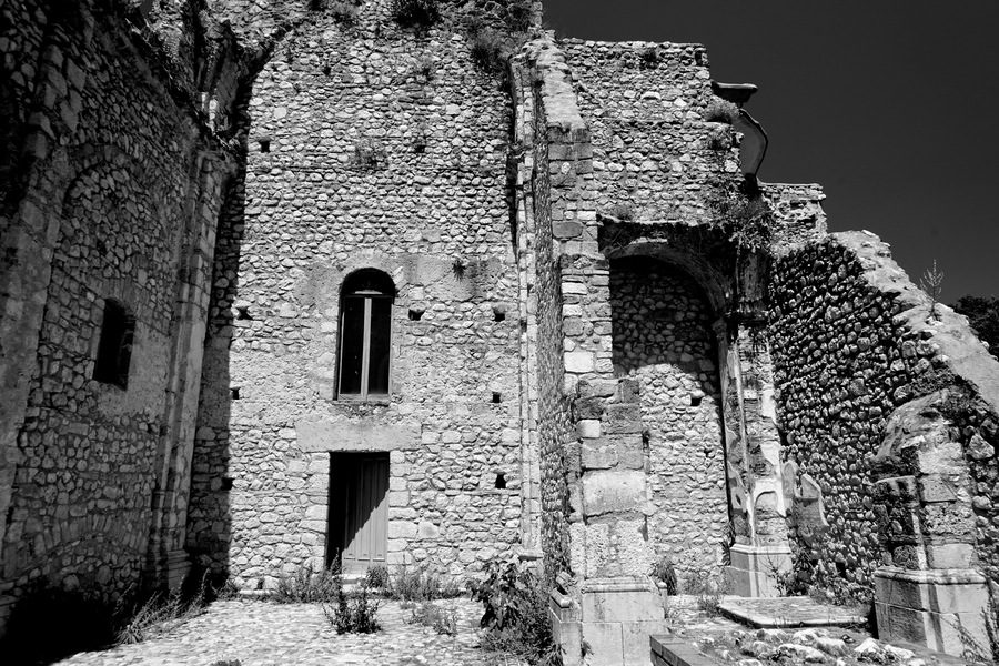 An ancient stone building with a central arched window and a staircase leading up to a higher level.
