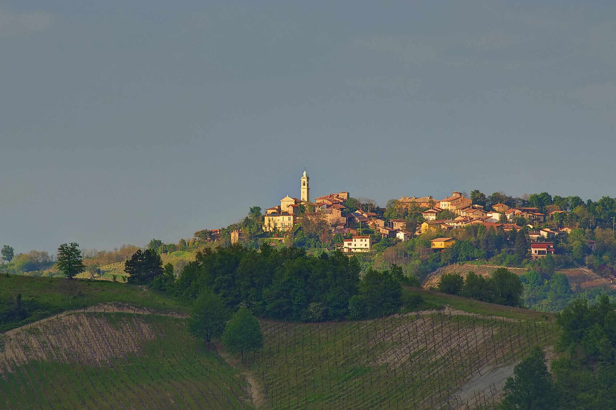 A hillside village with historic buildings and a prominent church tower.