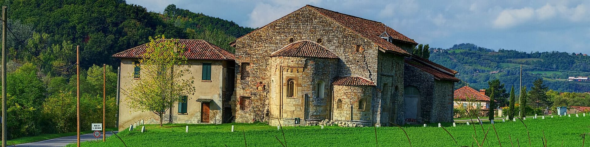 A stone building with a tiled roof in a rural setting.