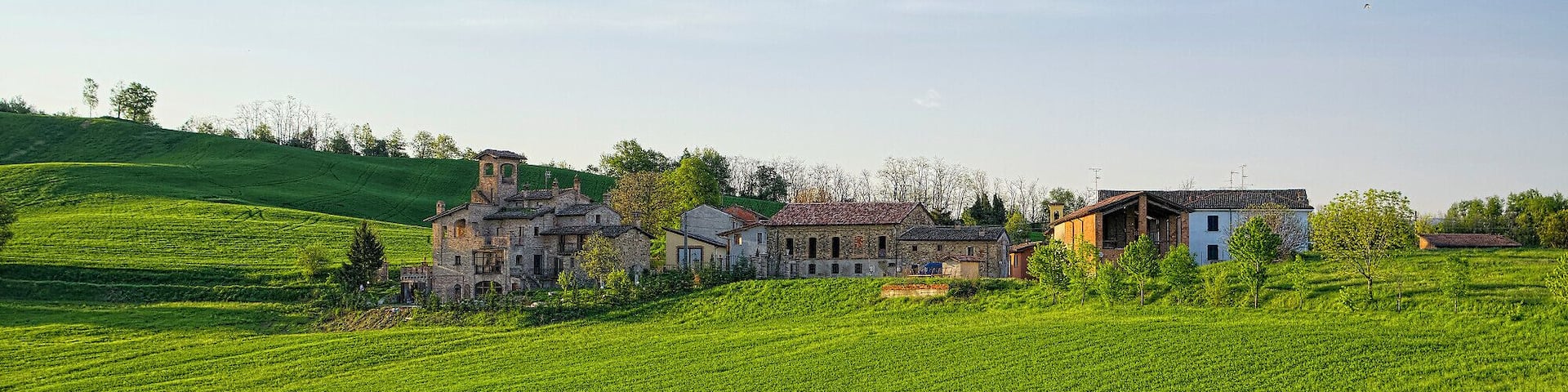 A rural landscape with rolling hills, a vineyard, and traditional stone houses.