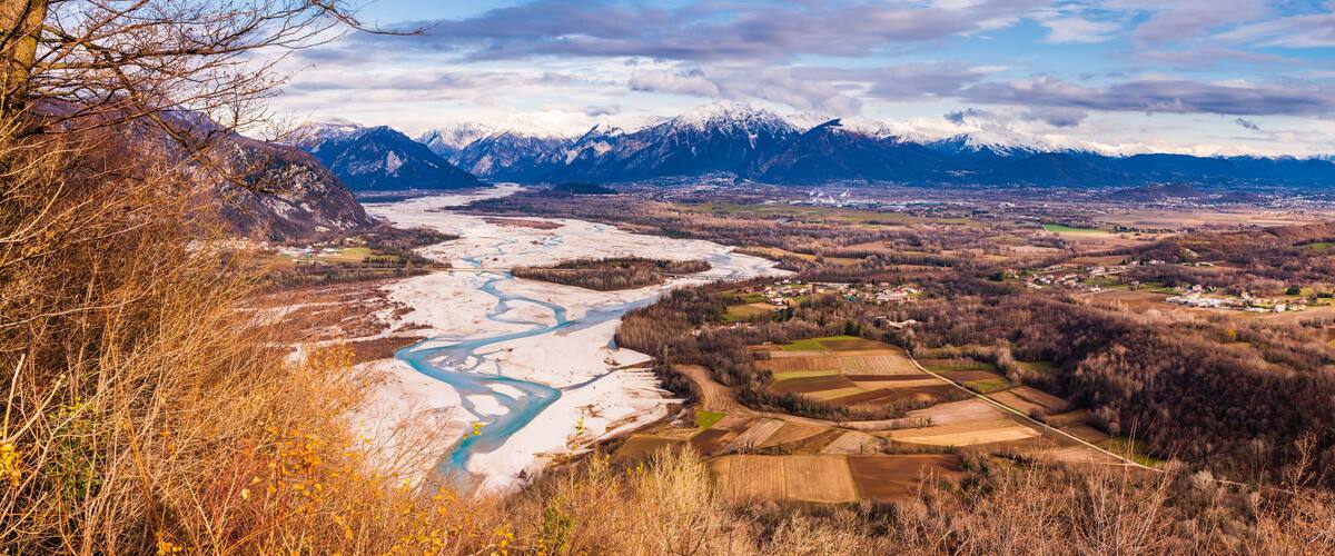 A river winding through a valley with snow-capped mountains in the background.