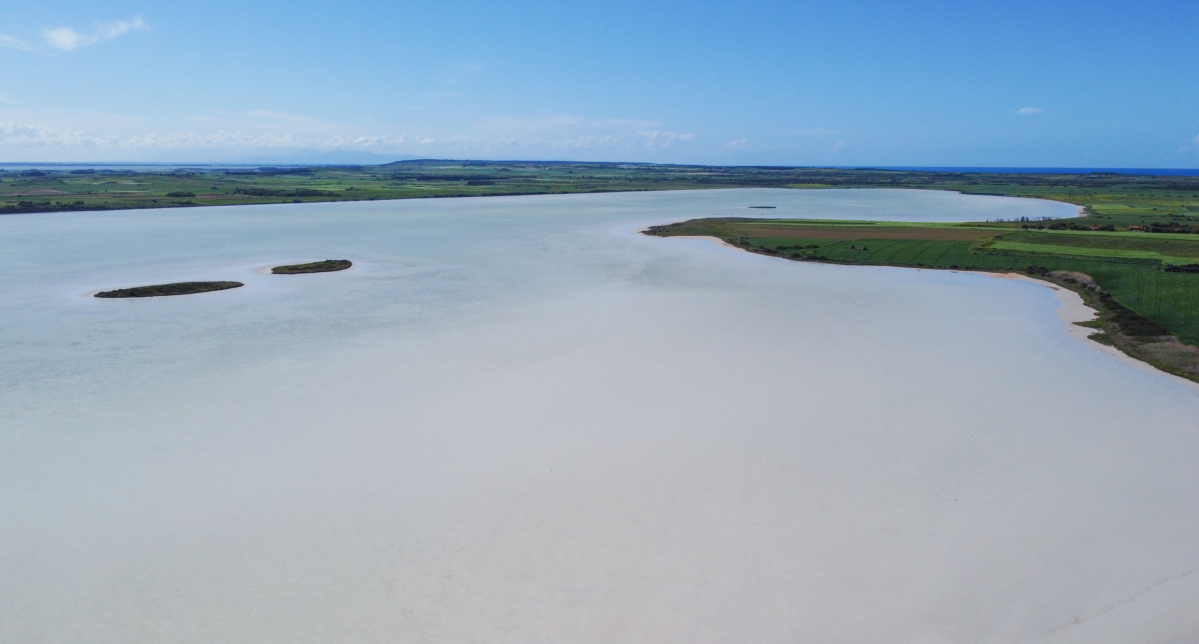 A river meandering through a green landscape with fields and small islands.
