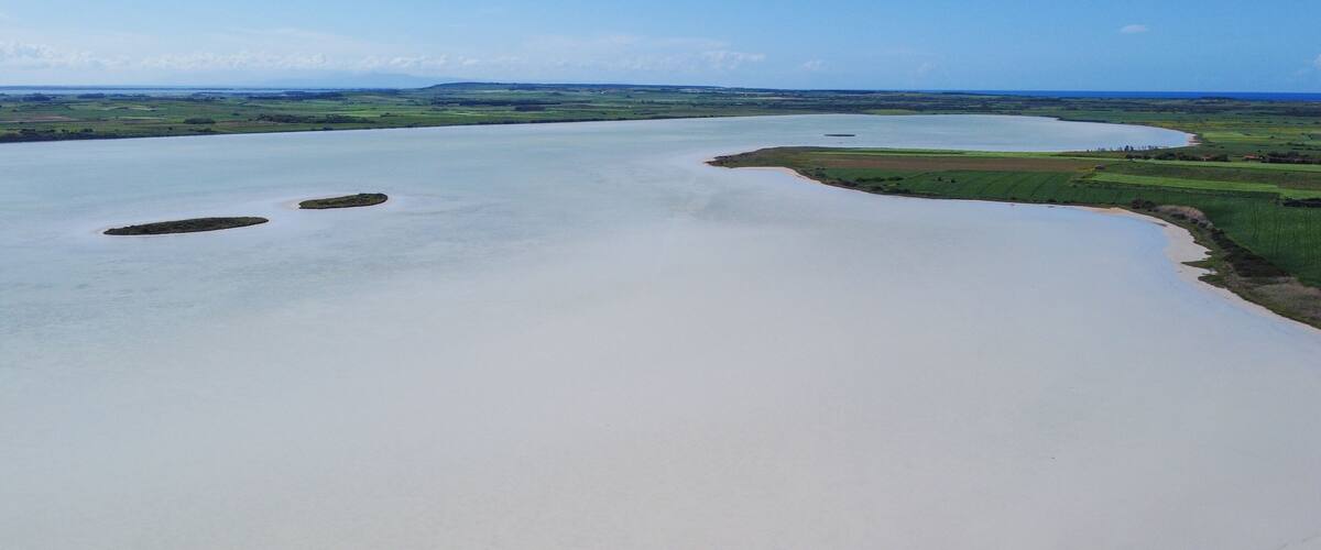A river meandering through a green landscape with fields and small islands.