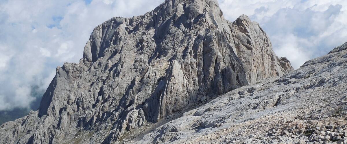 A rugged mountain peak with rocky terrain and sparse vegetation.