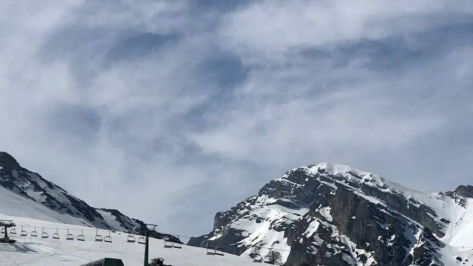 A snow-covered mountain with a ski lift and a clear sky.