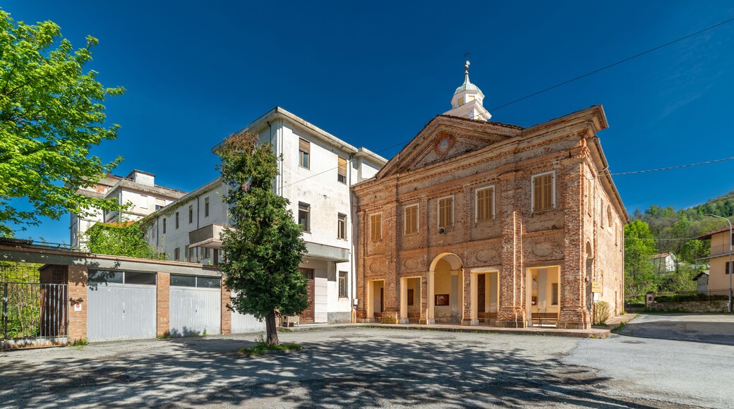 Peveragno, Cuneo, Italy - April 19, 2024: Shrine of Our Lady of the Woods or of the Borgato (13th cent.) near the abandoned building of the Salesian College from the 1960s-80s