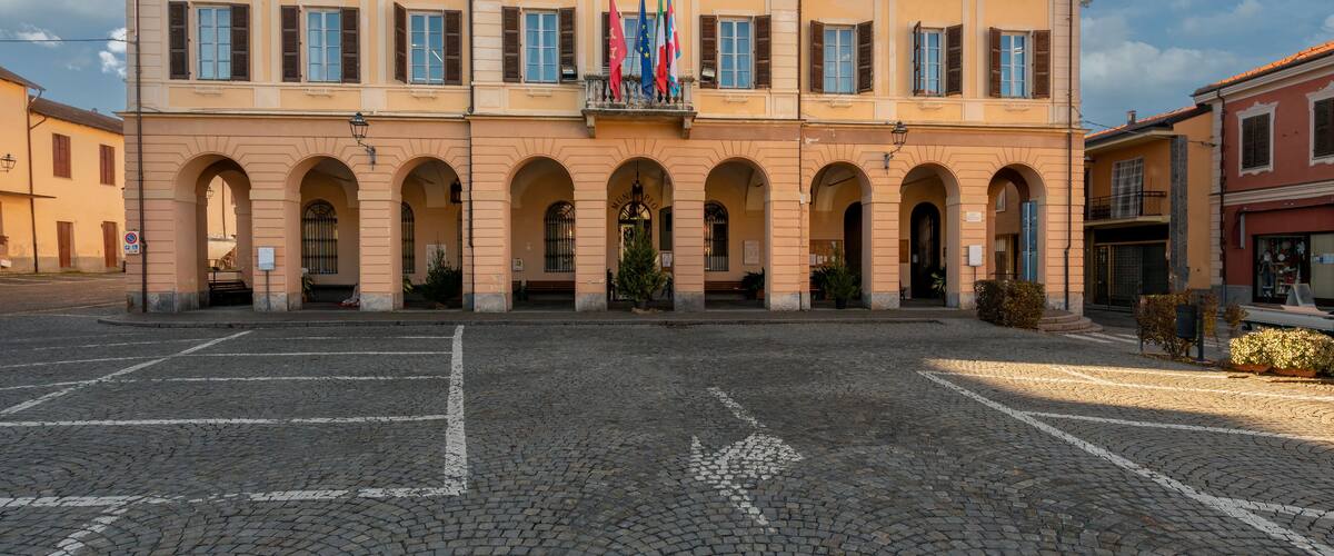 A historic building with a central balcony, arched windows, and multiple flags.