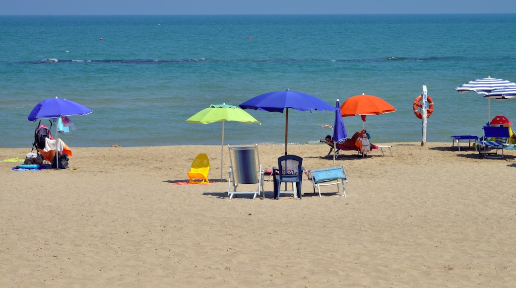 Una playa con varios sombrillas de colores, sillas y un flotador.