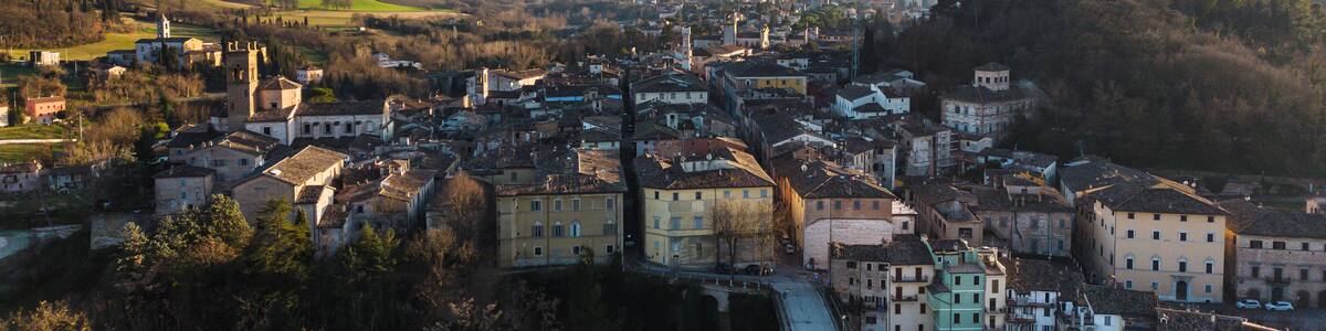 A historic town with a prominent church tower, a railway track, and rolling hills in the background.
