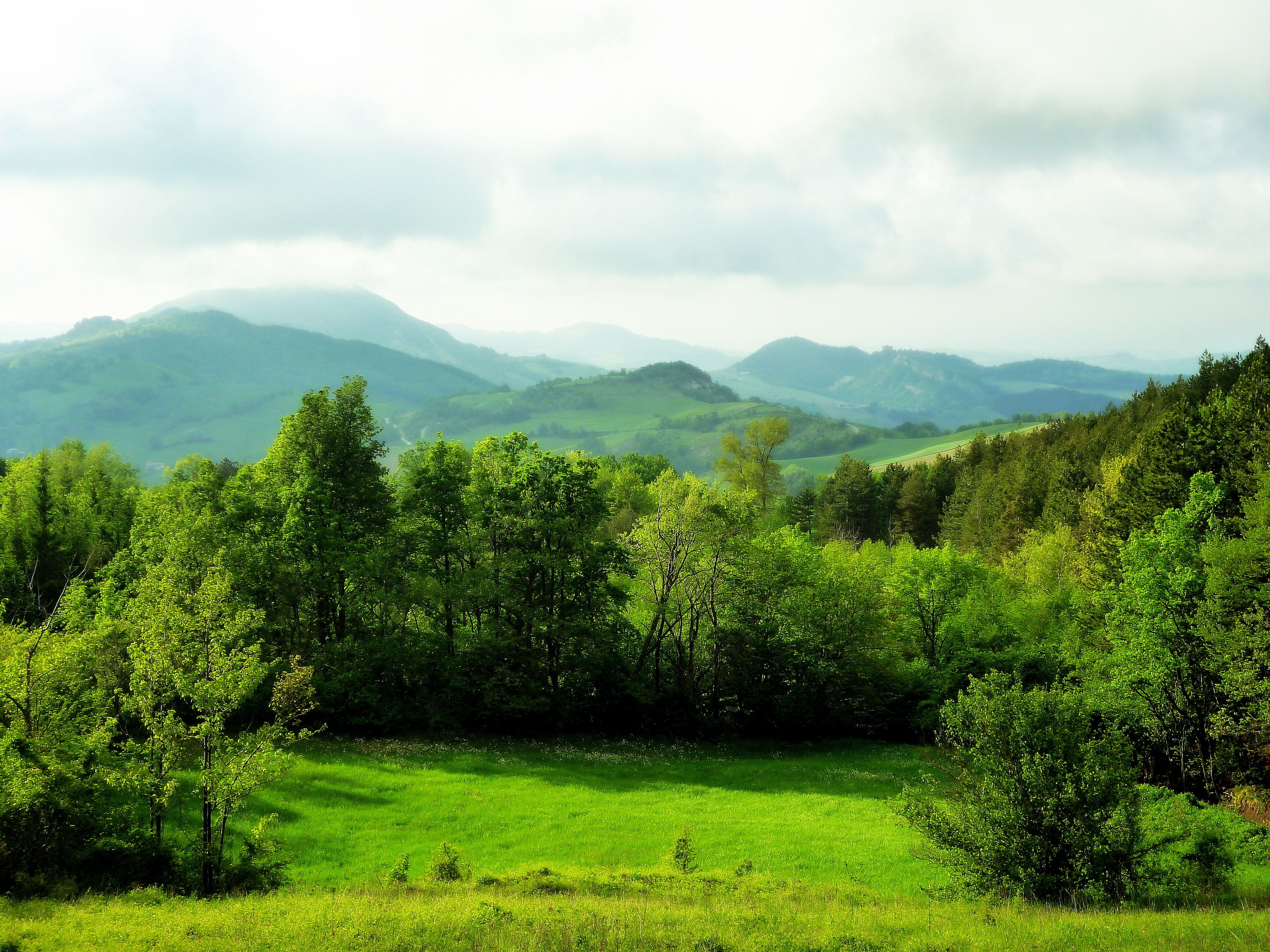 A lush green valley with rolling hills and a river in the distance.