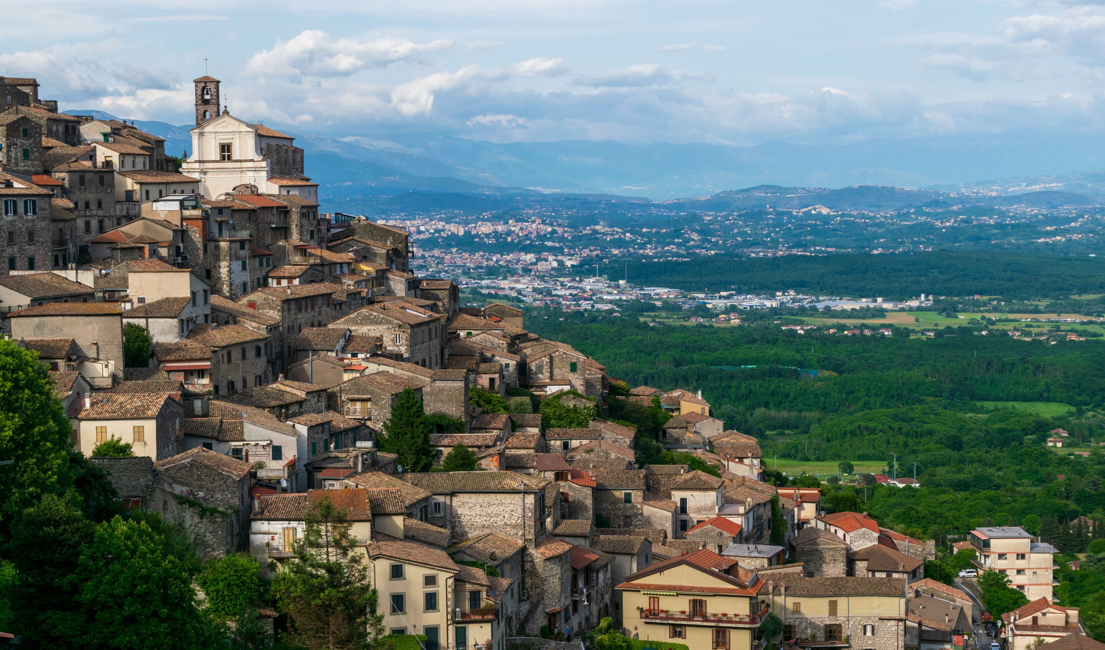 A historic town with stone buildings and a church on a hill overlooking a valley.