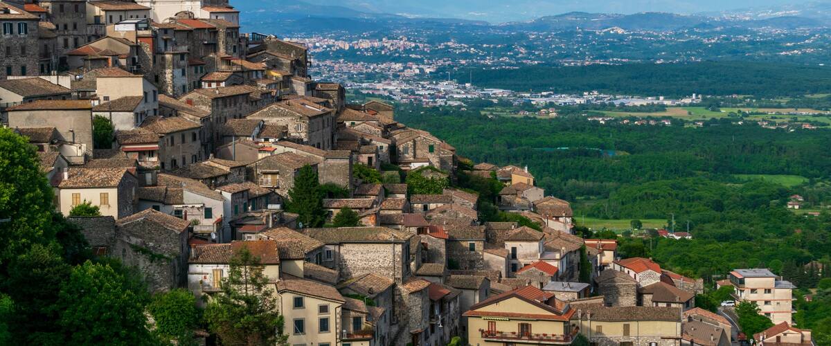 A historic town with stone buildings and a church on a hill overlooking a valley.