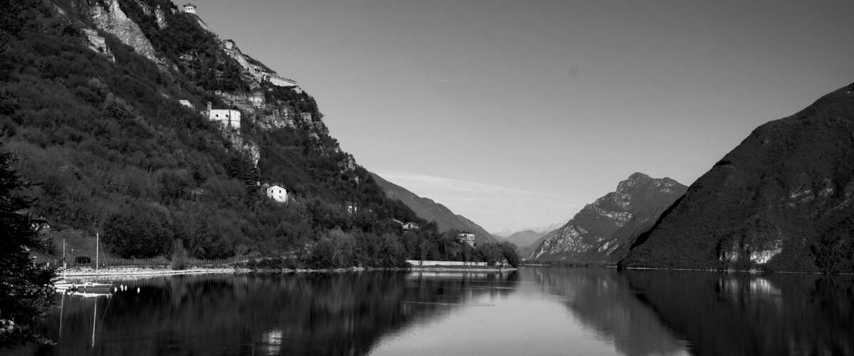 A calm river reflecting the surrounding mountains and buildings.