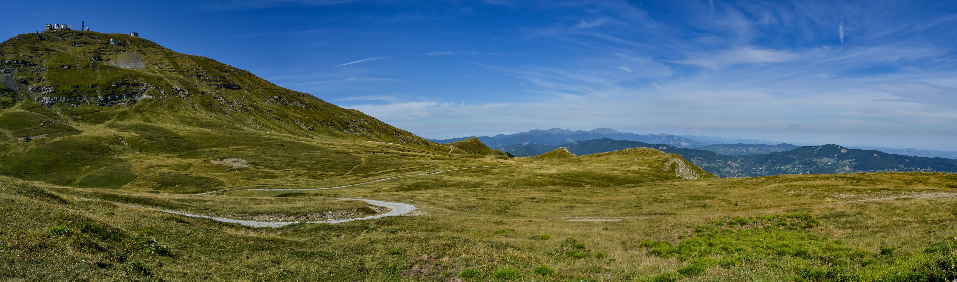 A mountainous landscape with a winding path and a small settlement on a hill.