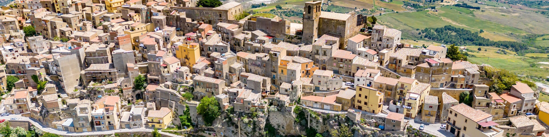 Un pueblo montañoso con edificios escalonados y una torre destacada.