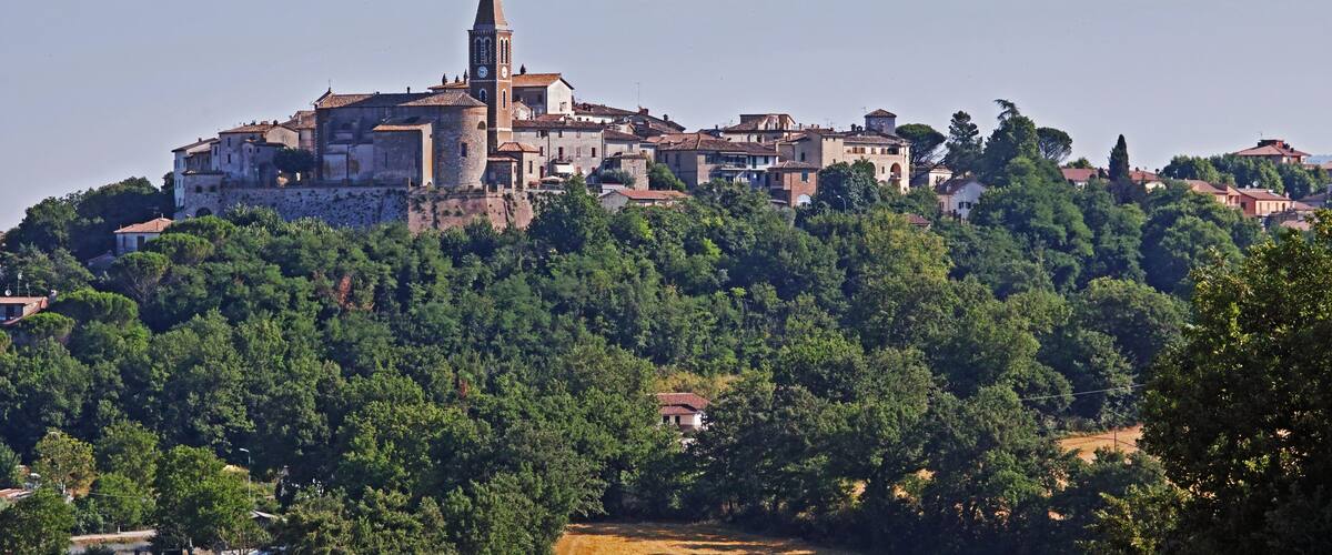 A historic town with a prominent church featuring a tall bell tower, surrounded by lush green hills.