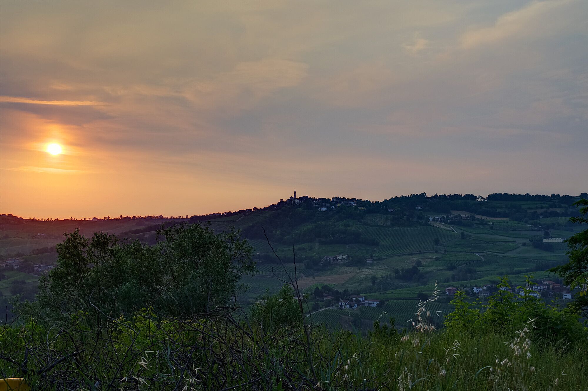 A sunset over rolling hills with a village in the distance.