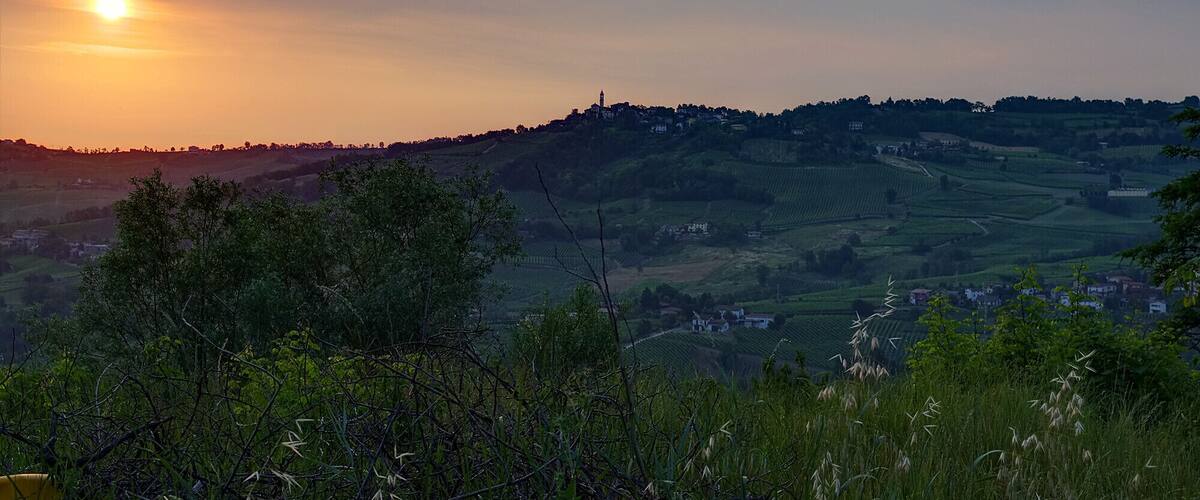 A sunset over rolling hills with a village in the distance.