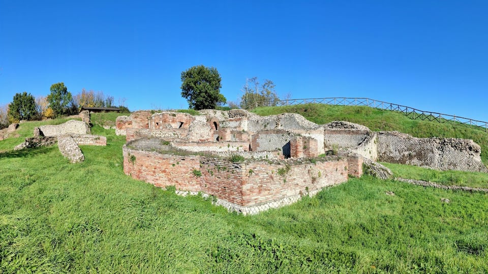 Ancient ruins on a grassy hill with a clear blue sky.