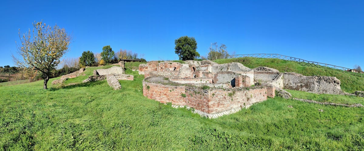 Ancient ruins on a grassy hill with a clear blue sky.