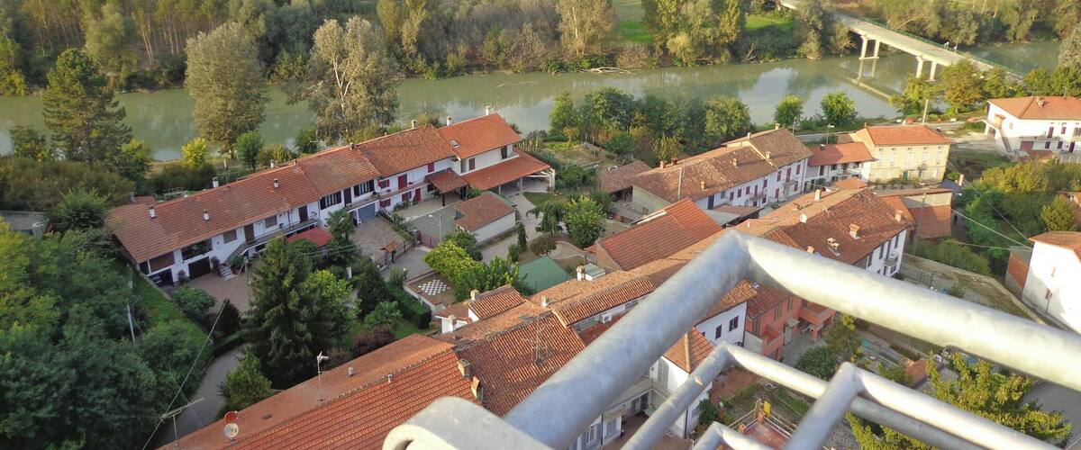 A rural landscape with fields, a river, and traditional buildings with red-tiled roofs.
