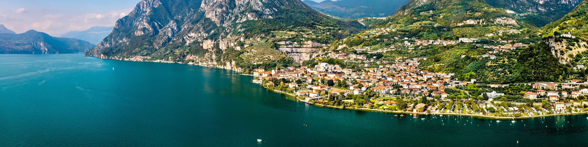 A coastal town nestled between mountains with a clear view of the sea and a prominent peak.