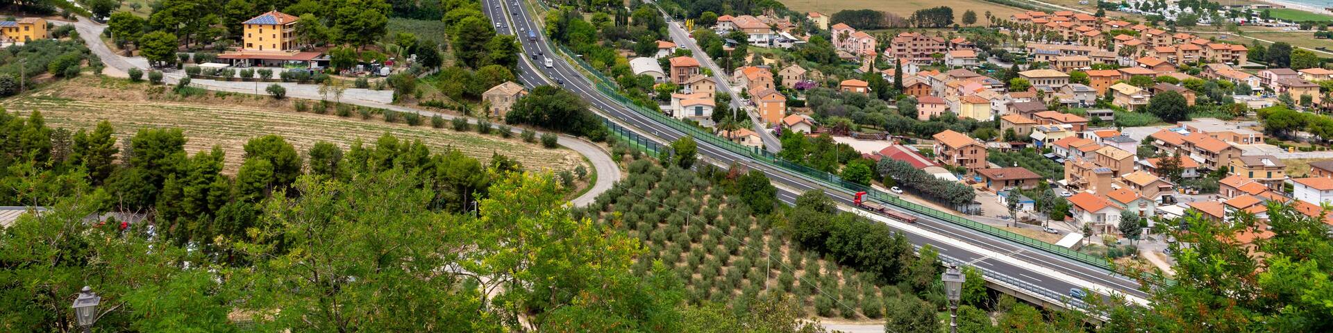 A coastal town with a winding road, green hills, and a beach.