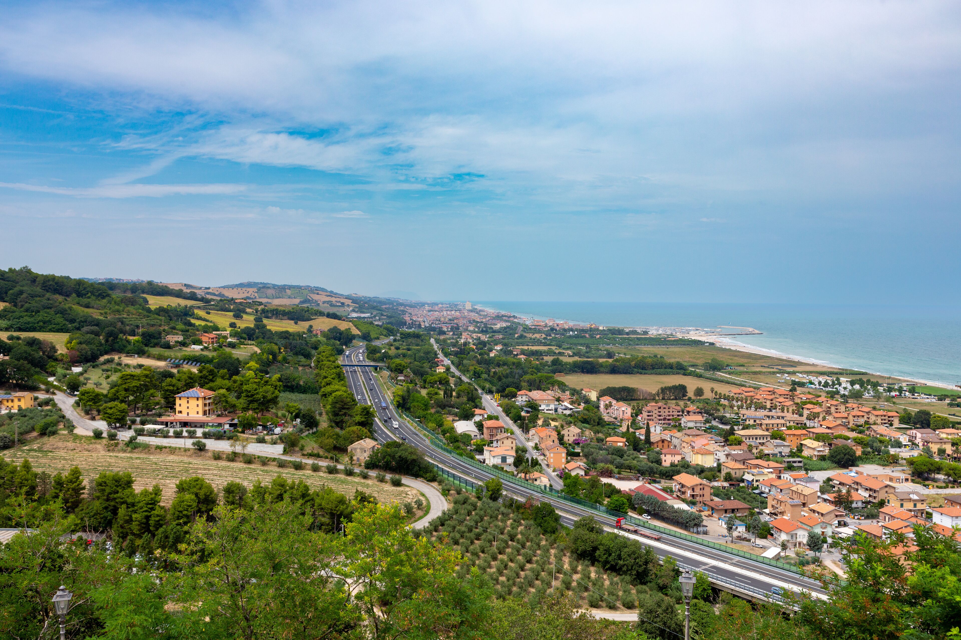 A coastal town with a winding road, green hills, and a beach.