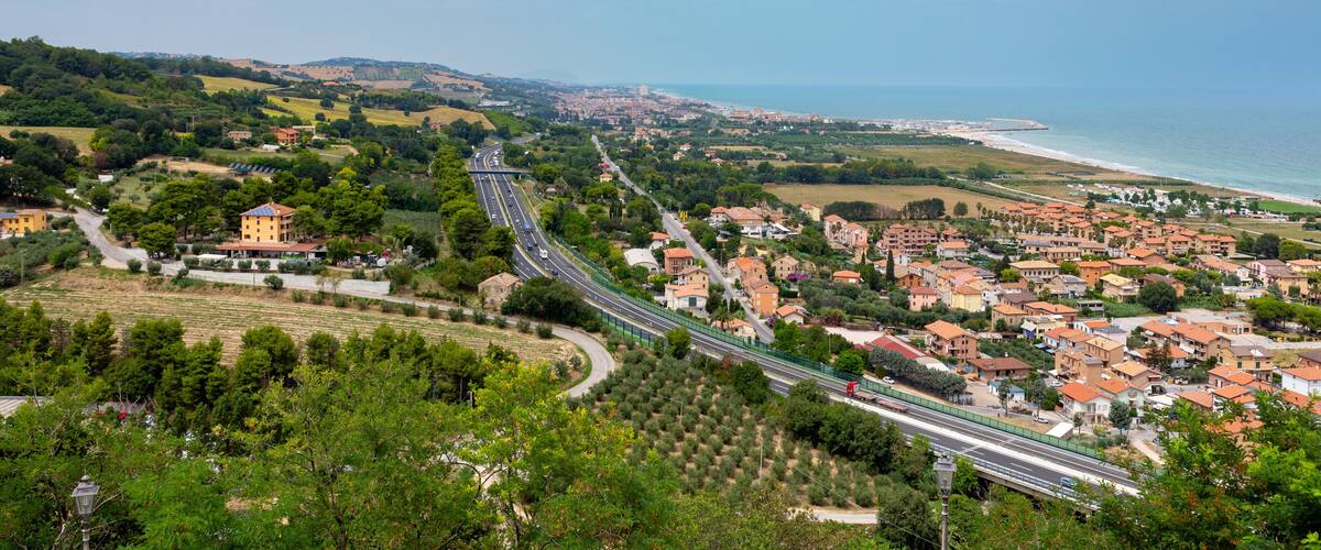 A coastal town with a winding road, green hills, and a beach.