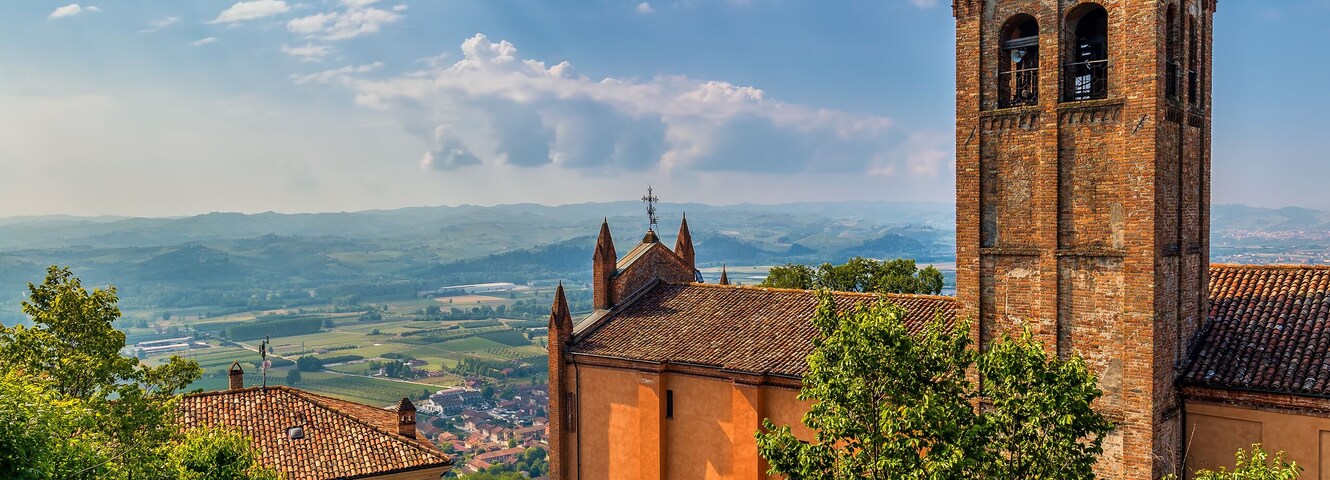 Old brick belfry under blue sky in small town in Italy.