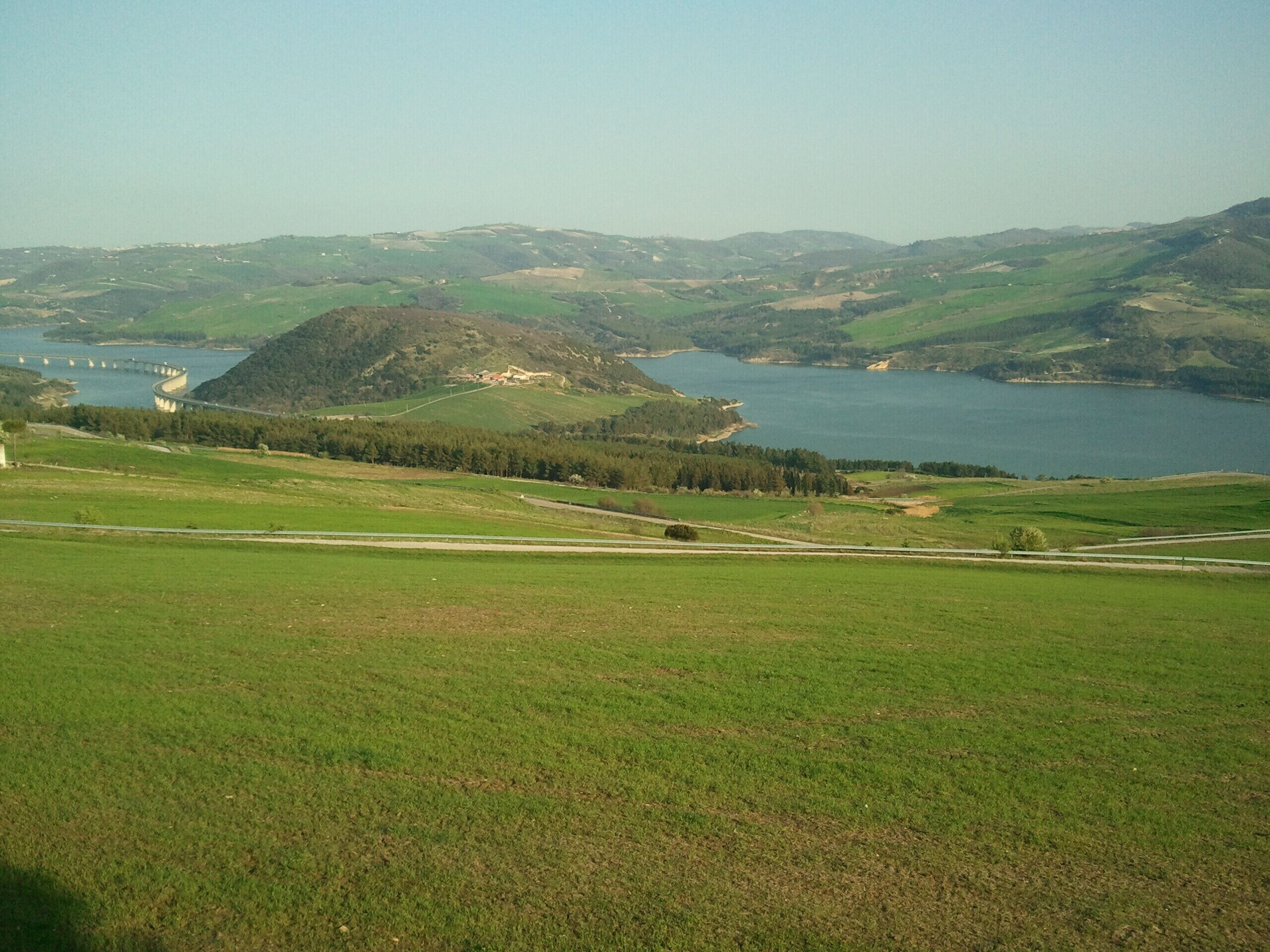 A green valley with a lake and a bridge.
