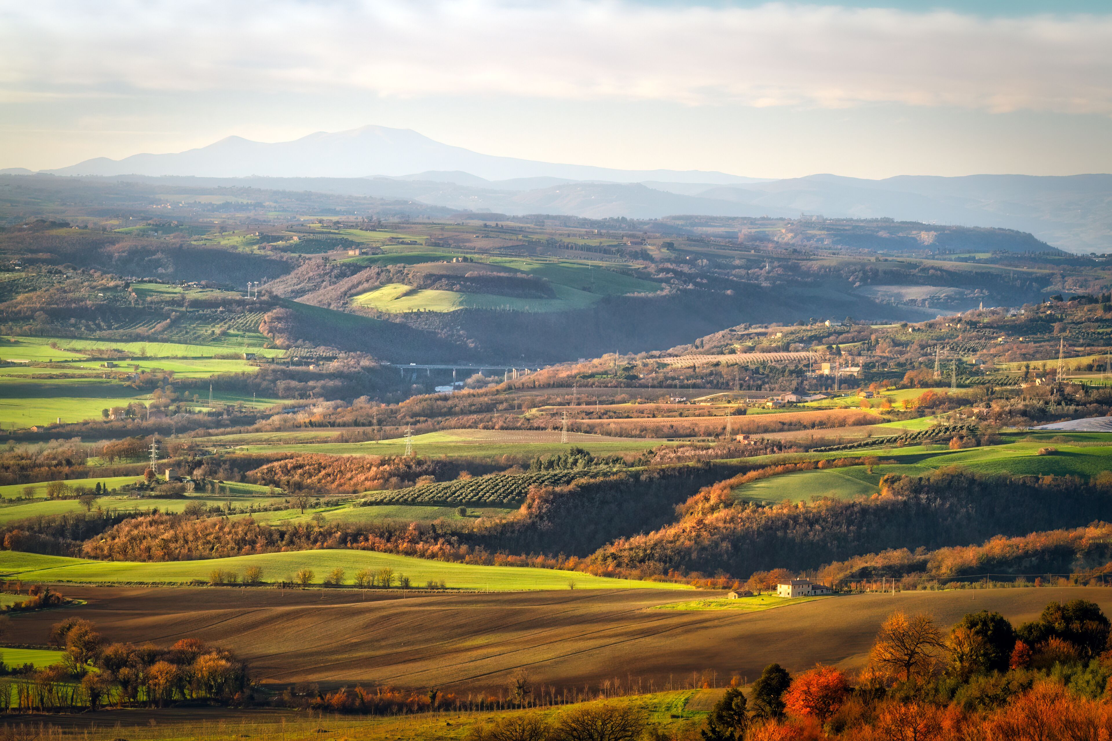 Rolling hills, fields, and distant mountains.