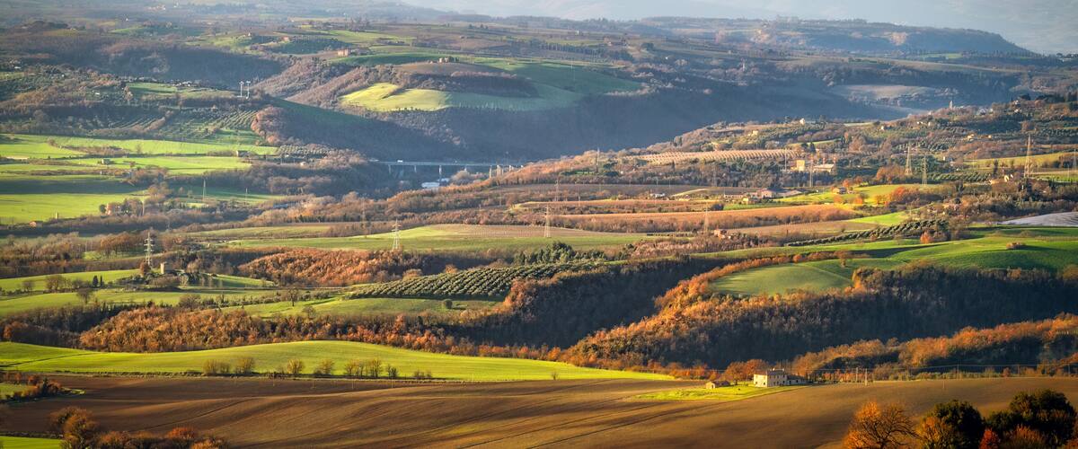 Rolling hills, fields, and distant mountains.