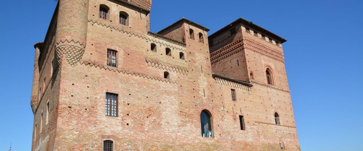 A large, historic brick castle with multiple towers and arched windows.