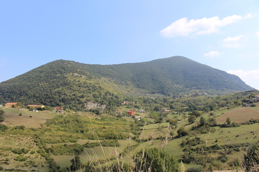 A mountain with a valley, houses, and greenery.