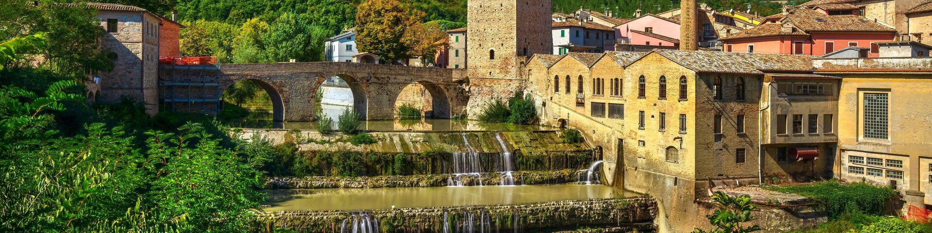 Roman bridge, medieval tower and Metauro river. Fermignano, Marche, Italy.