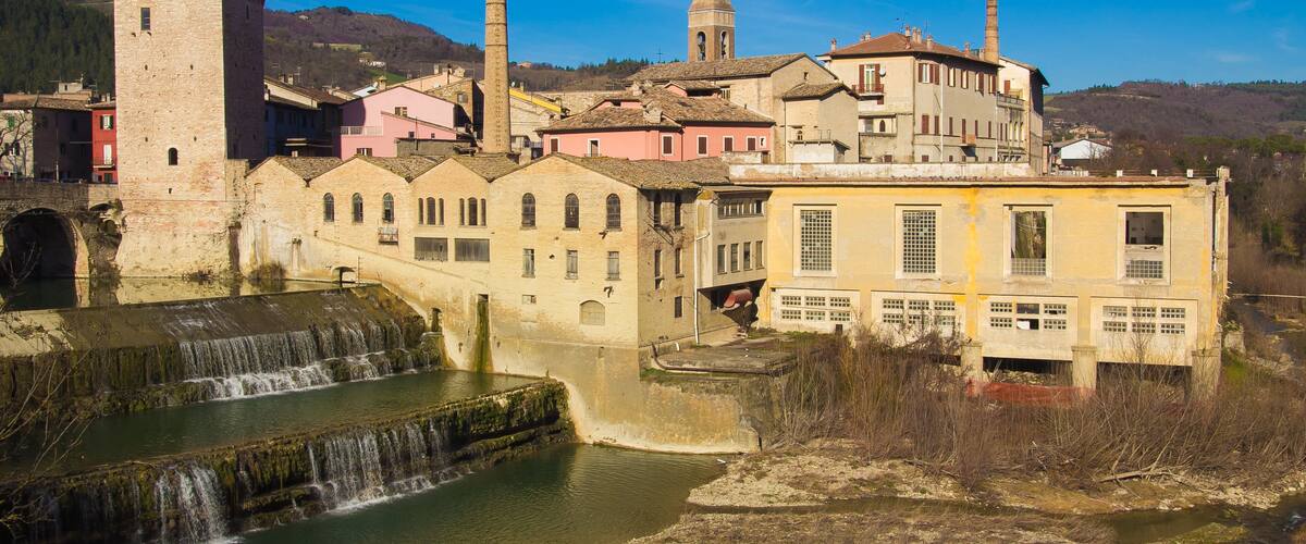 A historic town with a tower, watermill, and traditional buildings.