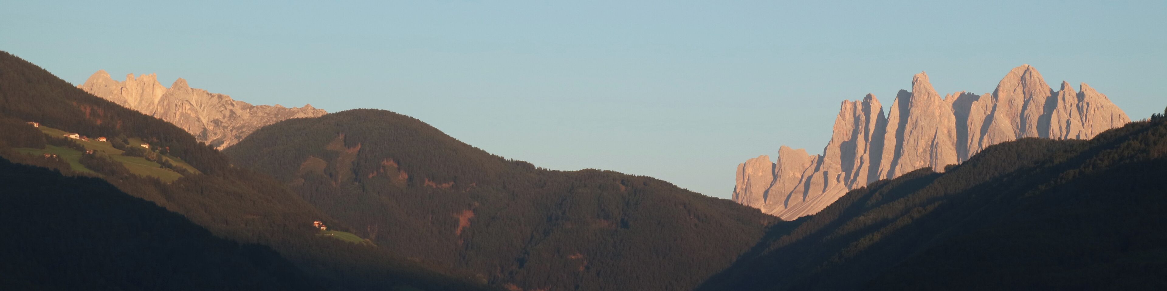 A mountainous landscape with a valley and a prominent rocky peak.