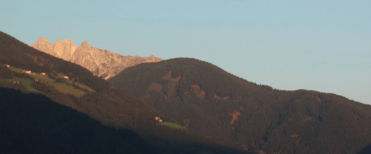 A mountainous landscape with a valley and a prominent rocky peak.