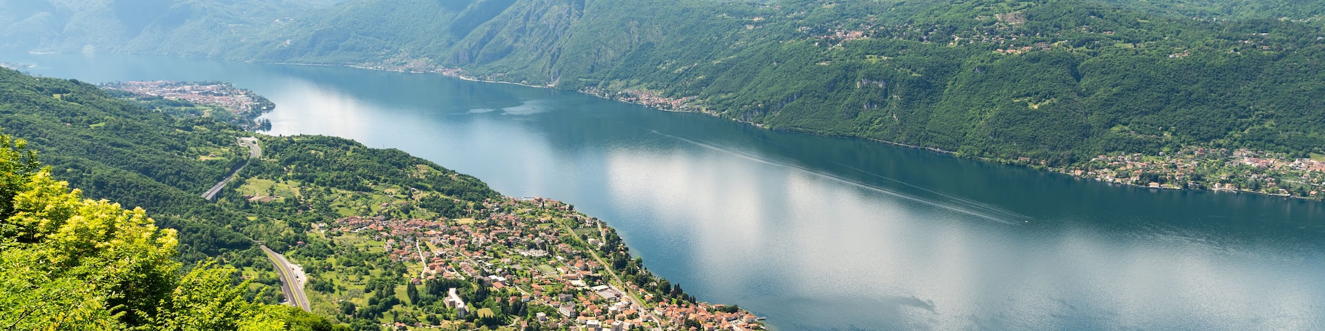Panorama of Lake Como photographed at Alpe Mezzedo in Esino Lario, showing Bellagio, Balbianello, the Lecco and Como shores of the lake and the mountains above.