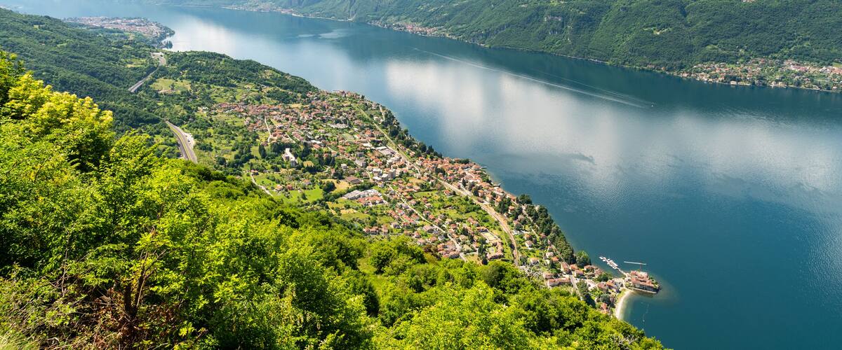 A mountainous landscape with a lake, a winding road, and a small town by the water.