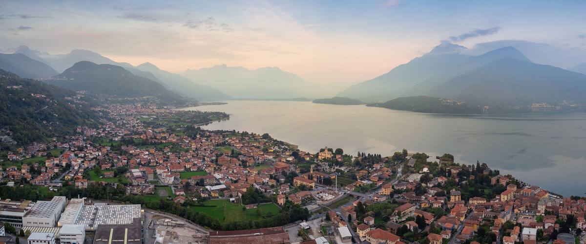 A panoramic view of a town nestled between mountains and a lake.