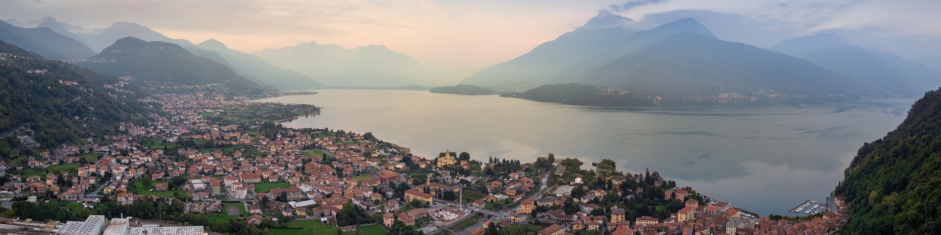 A panoramic view of a town nestled between mountains and a lake.