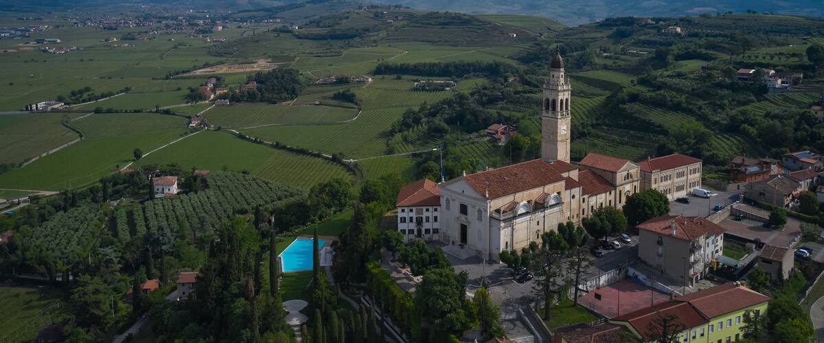 A town with a prominent church and tower, surrounded by green fields and rolling hills.