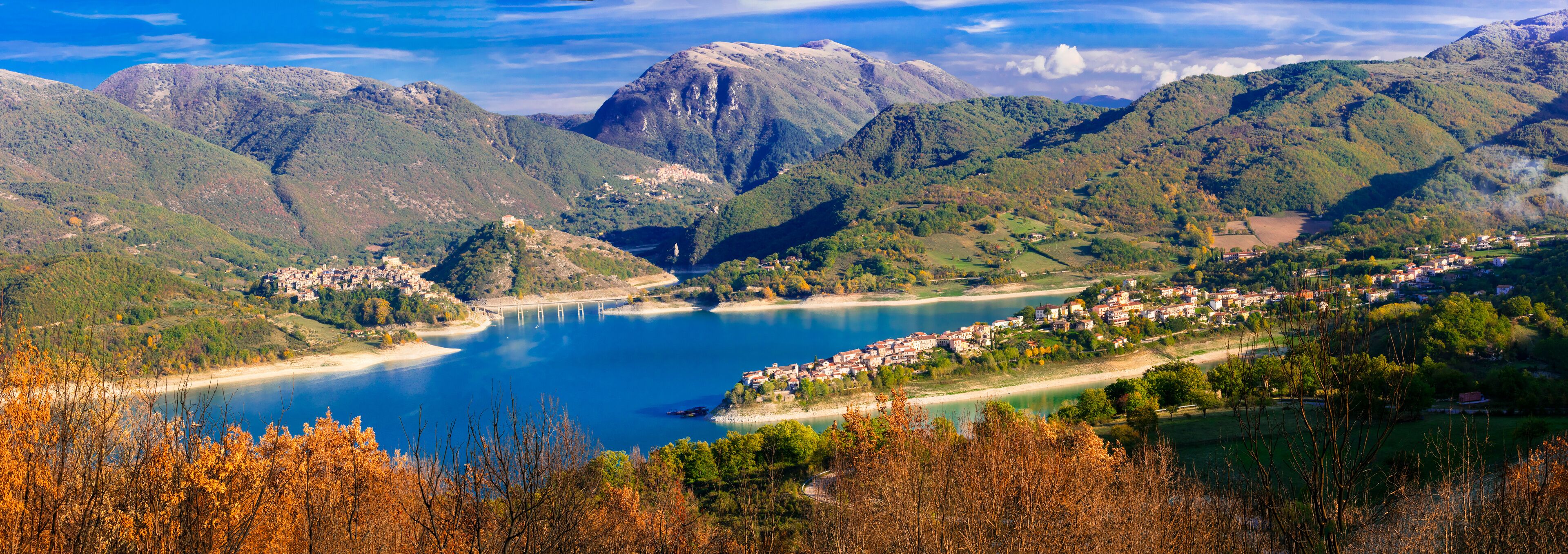 A mountainous landscape with a lake, a bridge, and a town.