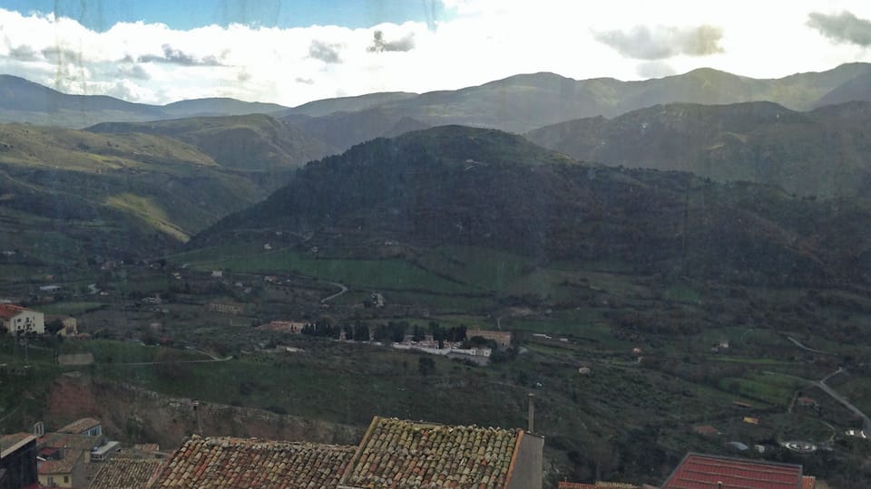 A mountainous landscape with terraced fields and traditional buildings with red-tiled roofs.
