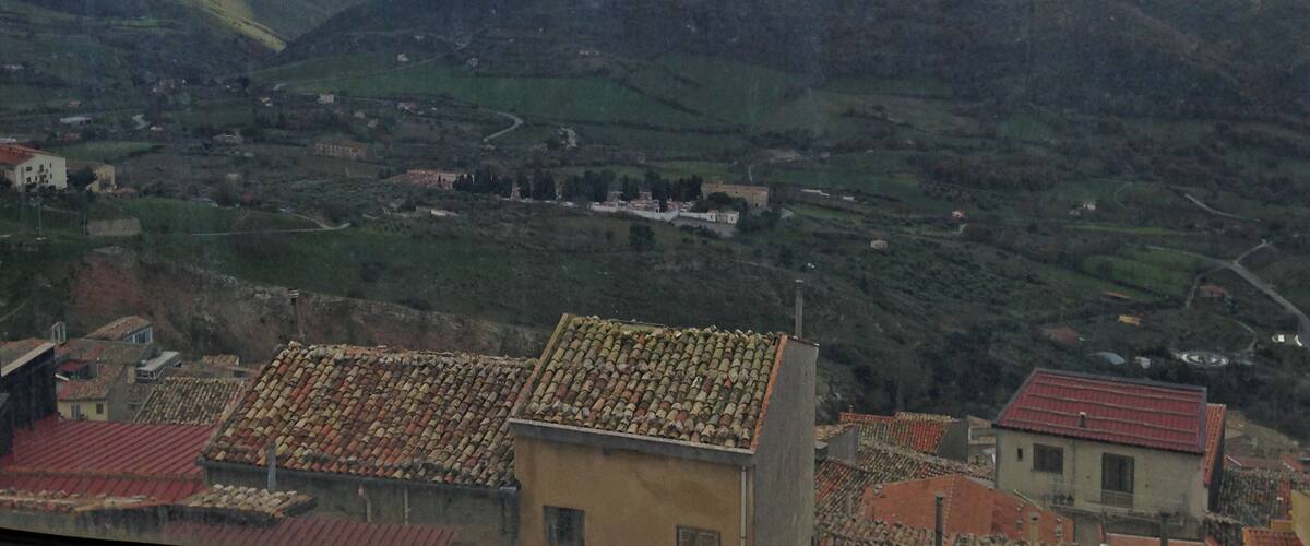 A mountainous landscape with terraced fields and traditional buildings with red-tiled roofs.