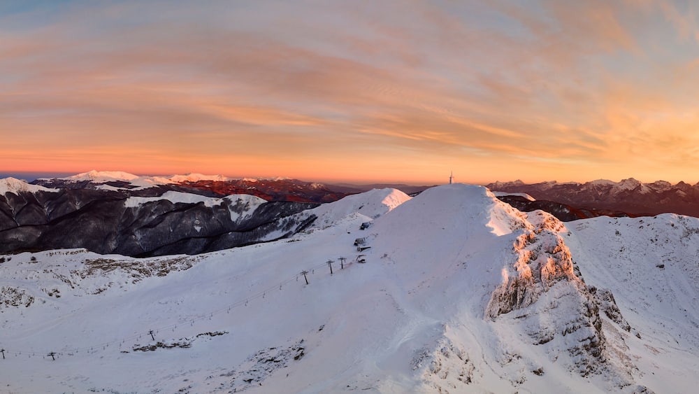A snow-covered mountain range at sunset with a clear sky.