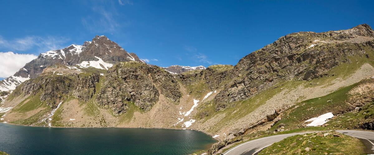 A mountain lake with a winding road and a prominent peak.