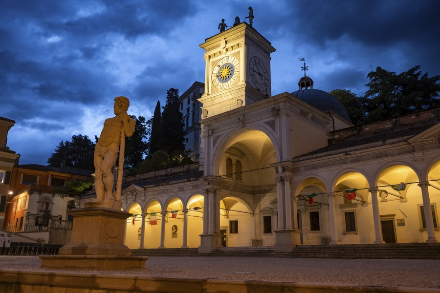 Ein historischer Platz mit einer Statue, einem Glockenturm und klassischer Architektur.